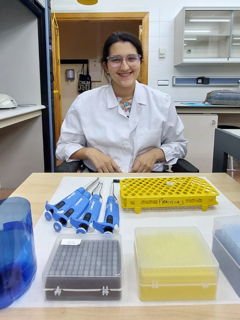 Paula sonriendo en el laboratorio en su puesto adaptado.