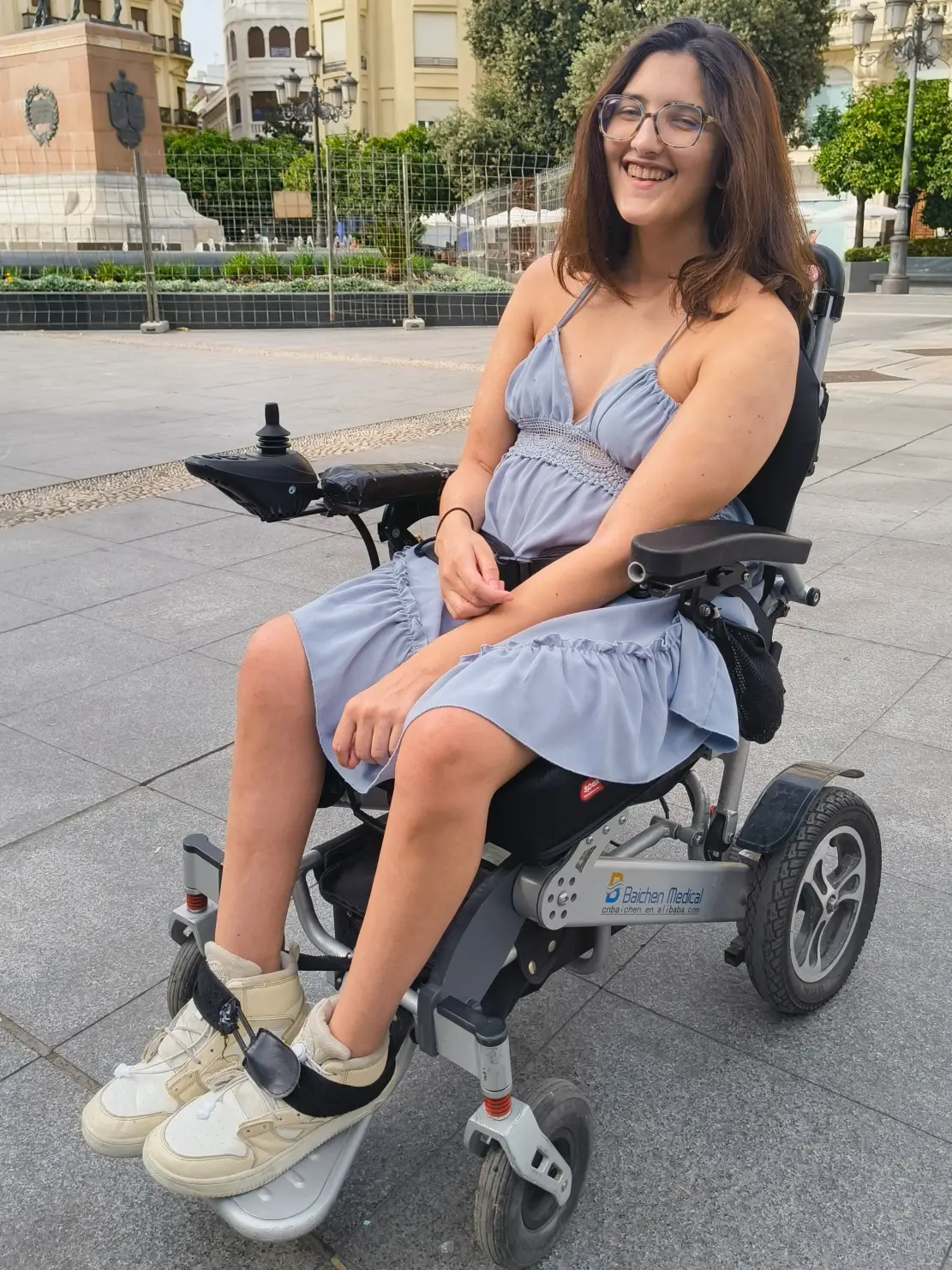 Paula sonriendo en su silla en la Plaza de las Tendillas, Córdoba, España.